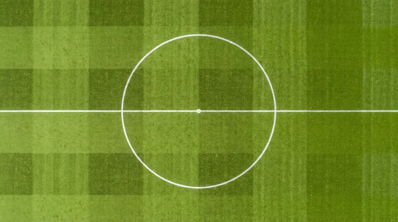 Jalkapallokentän keskiympyrä ja keskipiste kuvattuna ylhäältä päivänvalossa