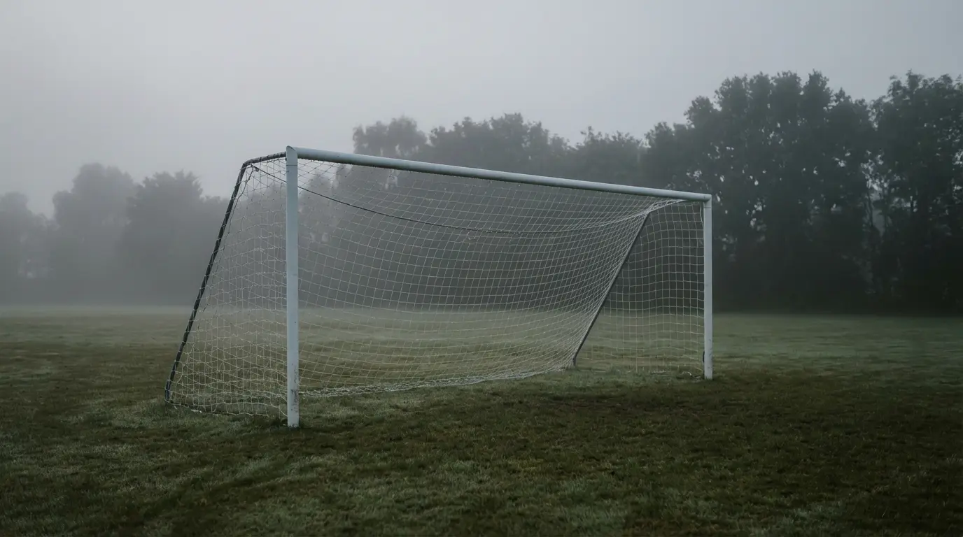 Jalkapallomaali verkkoineen tyhjällä kentällä aamusumussa